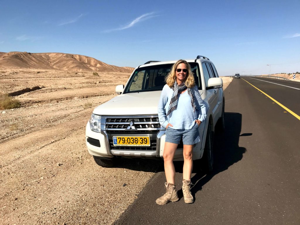 Frau vor einem Geländewagen in Israel am Highway in der Wüste
