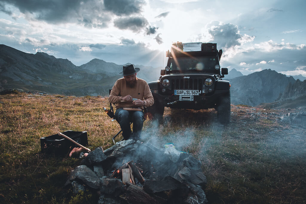 Camping-Rezepte: Mann sitzt am Lagerfeuer
