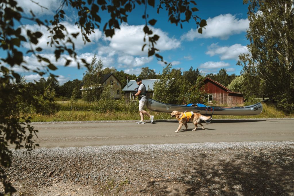 Kanutour Schweden Mann mit Hund zieht Kanu über Land