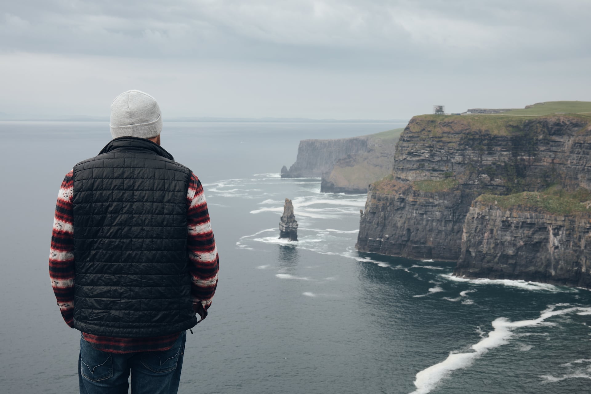 Mann steht vor den Cliffs of Moher in Irland