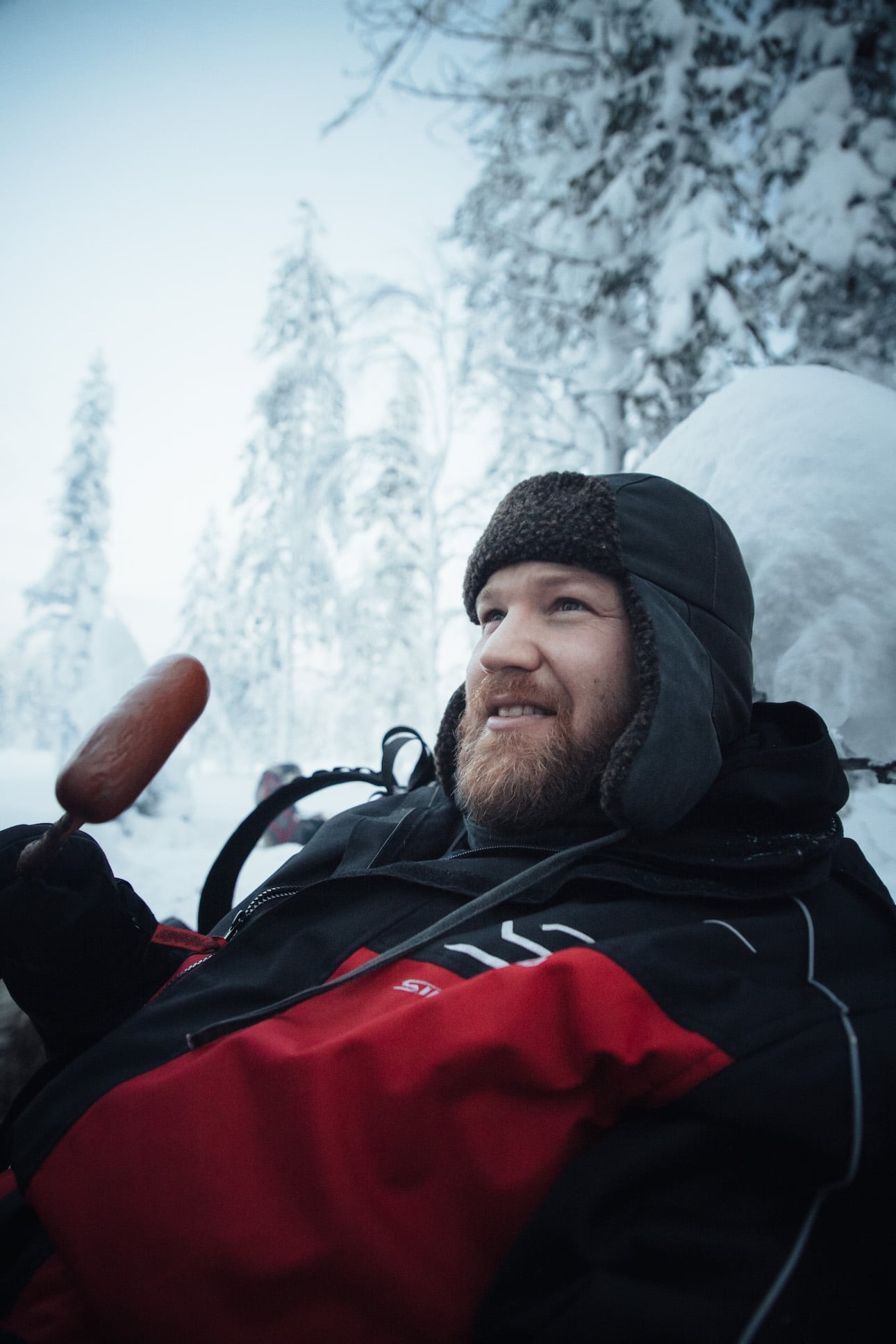 Mann isst finnisch Wurst am Lagerfeuer auf Huskytour