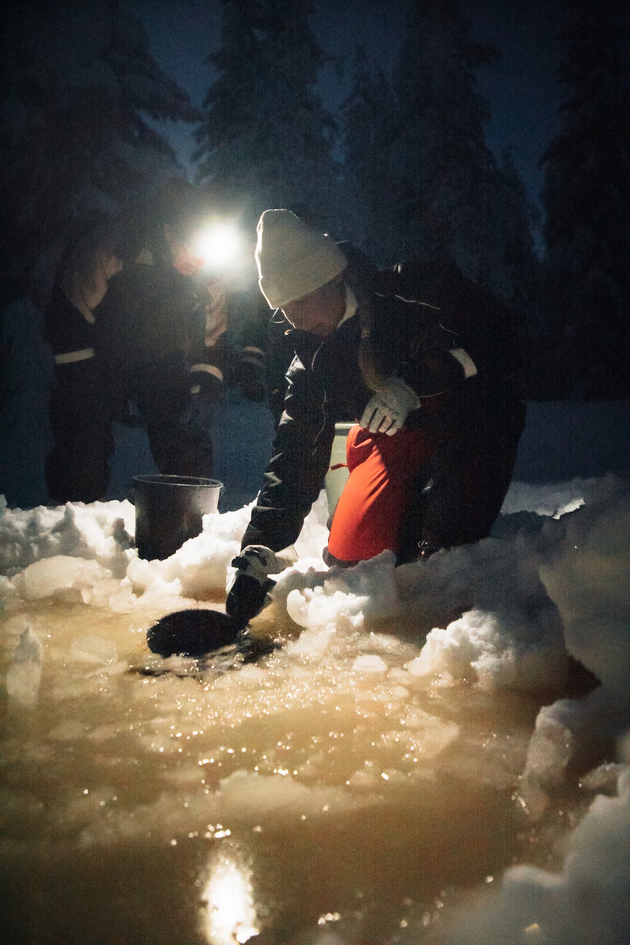Frau schöpft Wasser aus Eisloch in Finnland