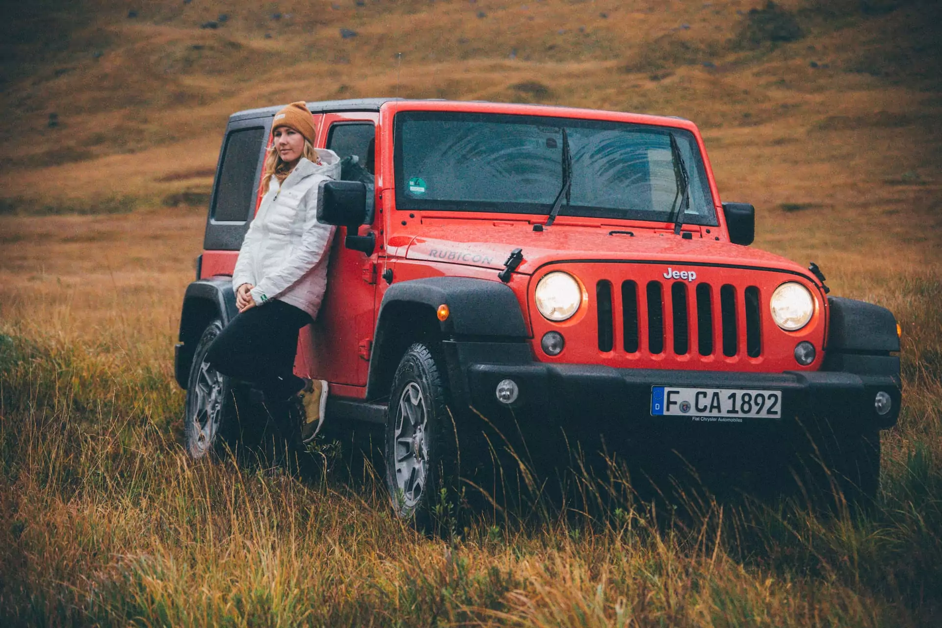Roadtrip durch Schottland: Frau steht am Auto in der wilden Natur