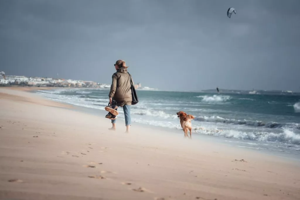 Frau spaziert mit Hund am Strand von Tarifa in Andalusien