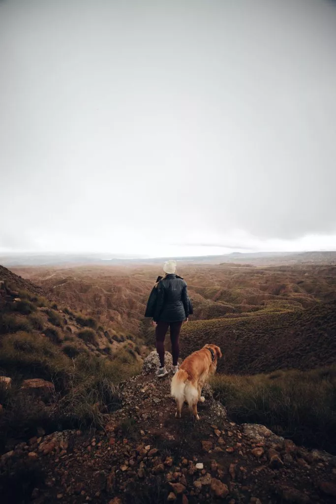 Frau mit Hund wandert durch die Wüste von Gorafe