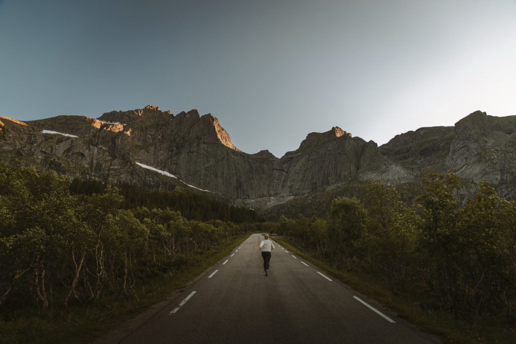Frau rennt über Straße auf Camping-Trip durch Norwegen