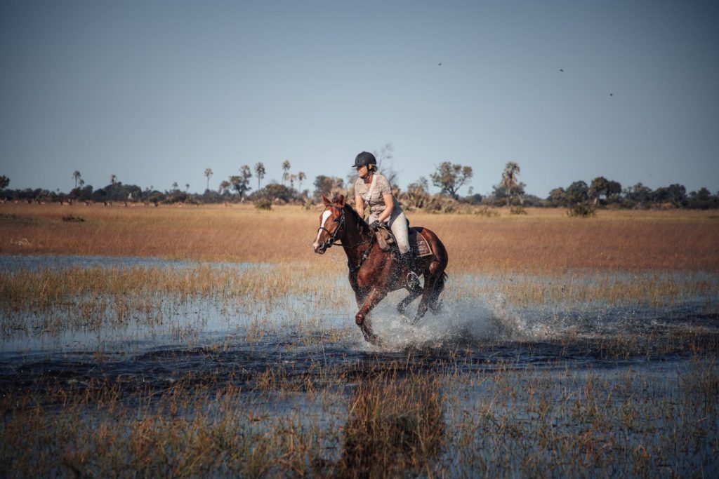 Frau galoppiert durch die Flut im Okavango Delta