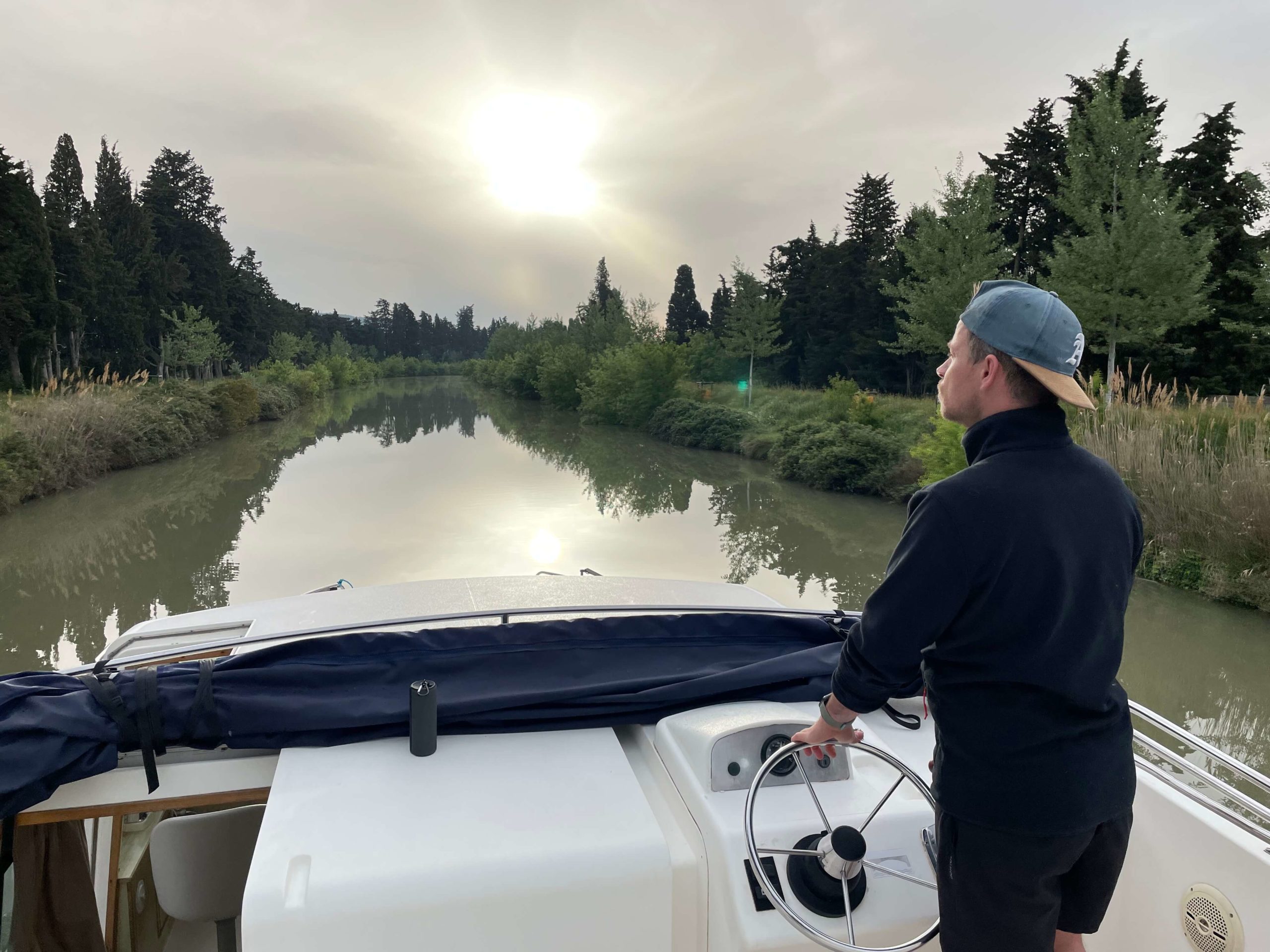 Mann steuert Hausboot auf einem Kanal
