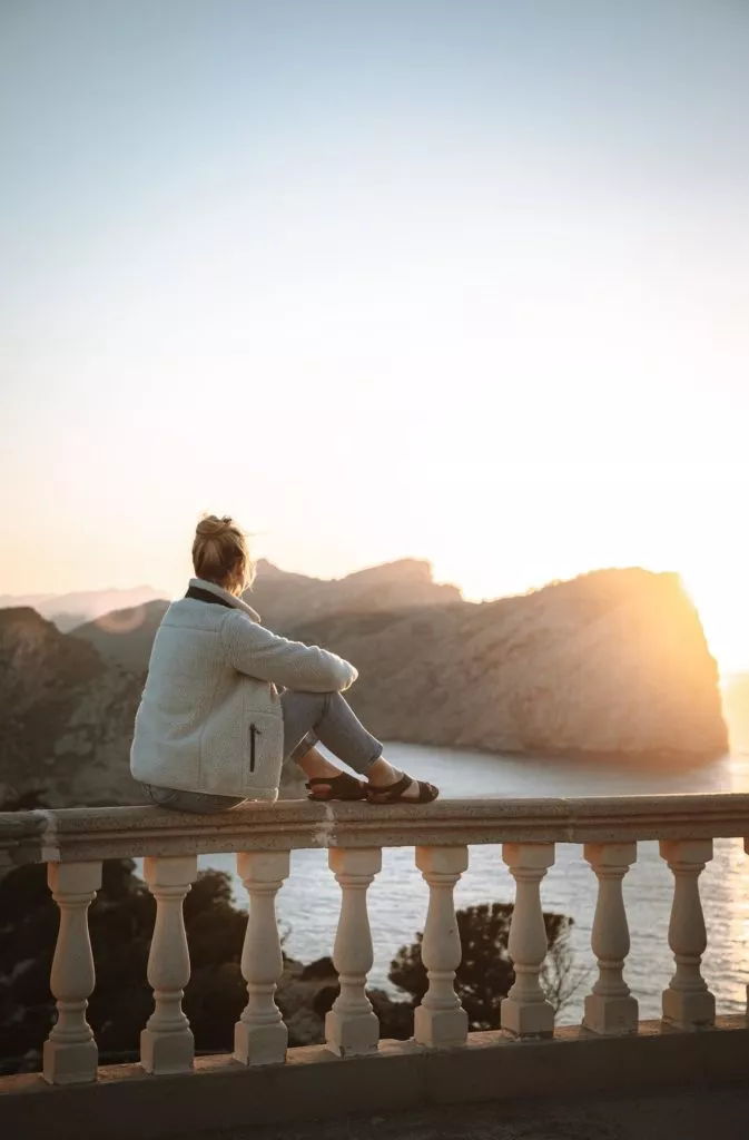 Frau schaut sich den Sonnenuntergang am Cap de Formentor in Mallorca an
