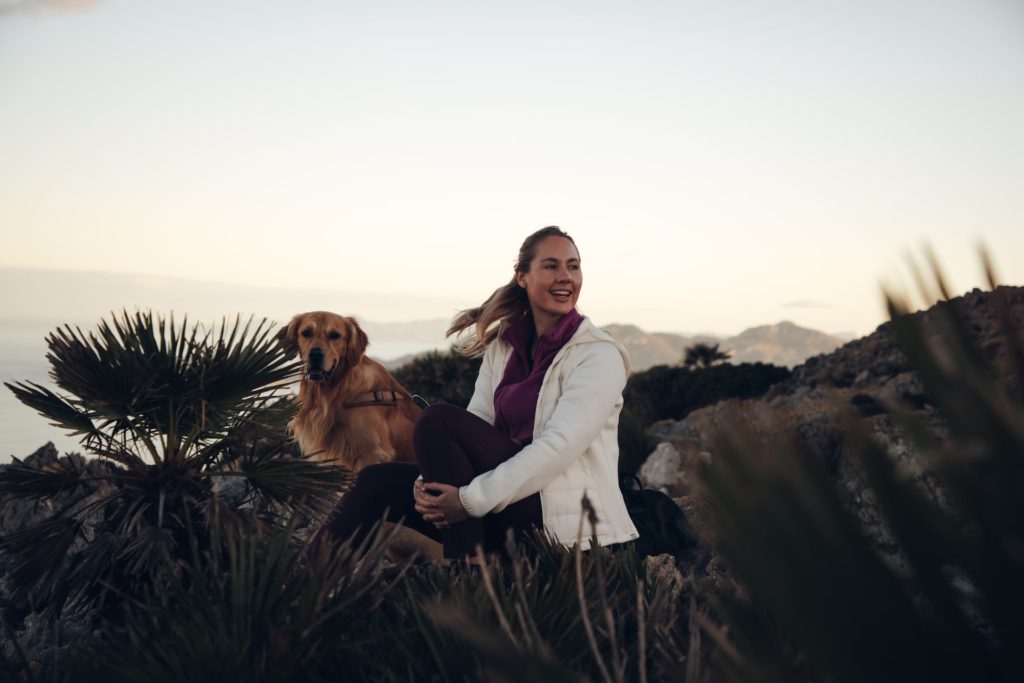 Frau genießt Pause beim Wandern mit Hund auf Mallorca