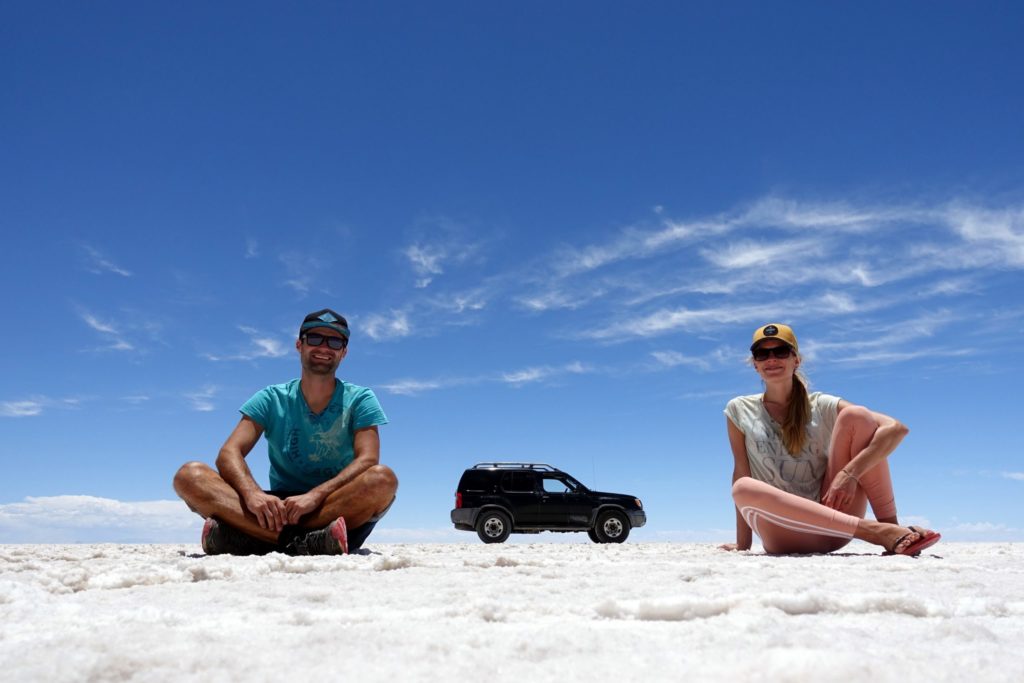 Mann und Frau mit Auto in Salzwüste