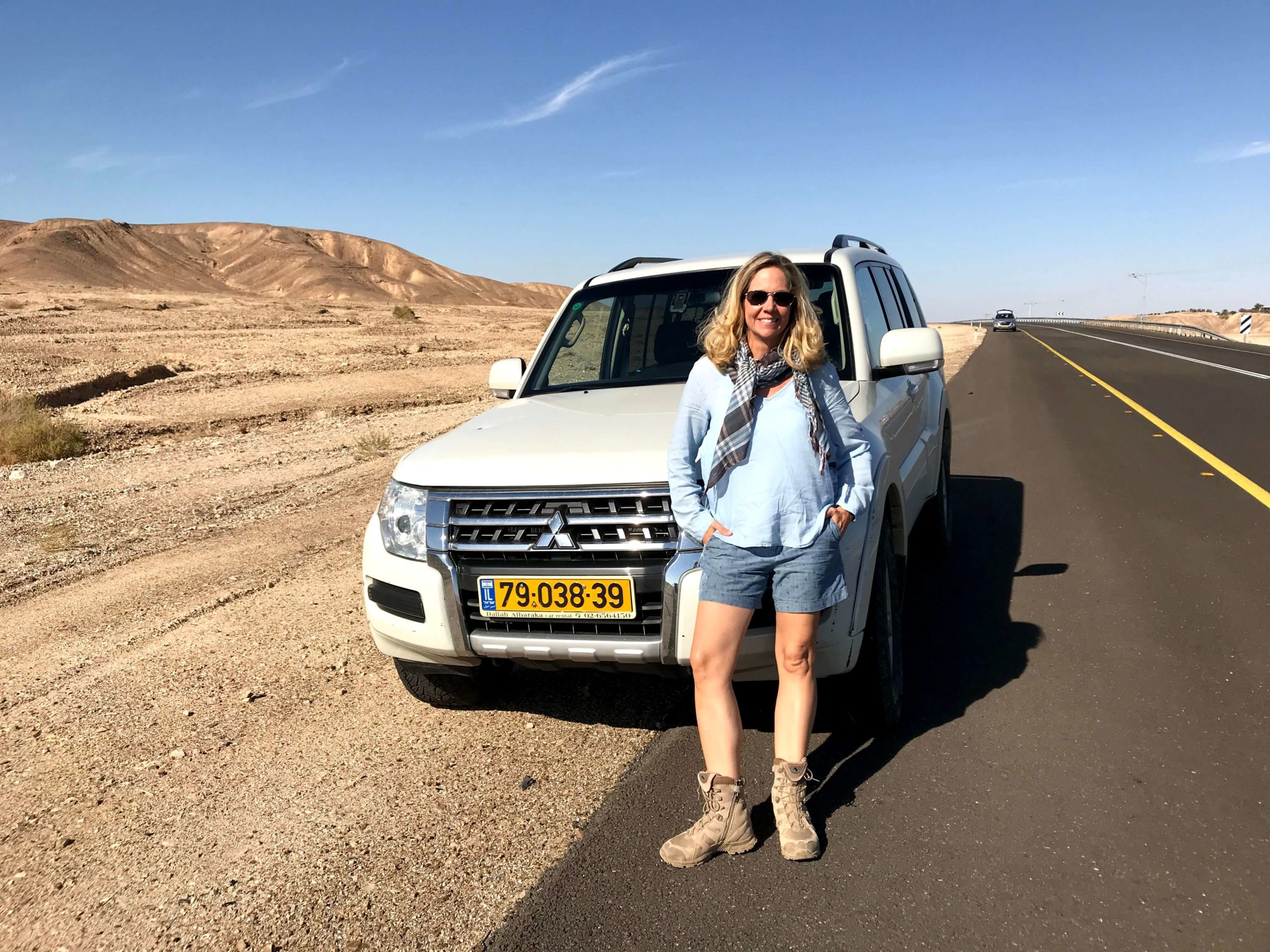 Frau vor einem Geländewagen in Israel am Highway in der Wüste