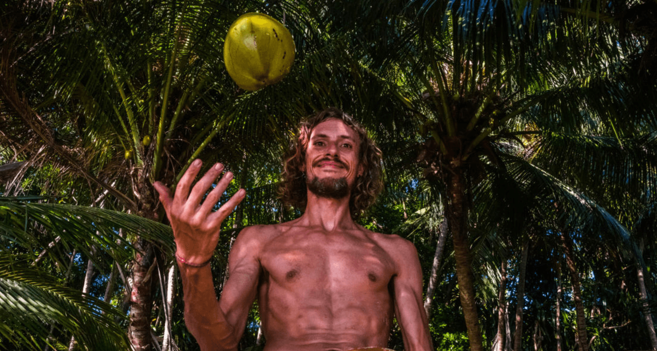 Mann wirft Kokosnuss in die Höhe