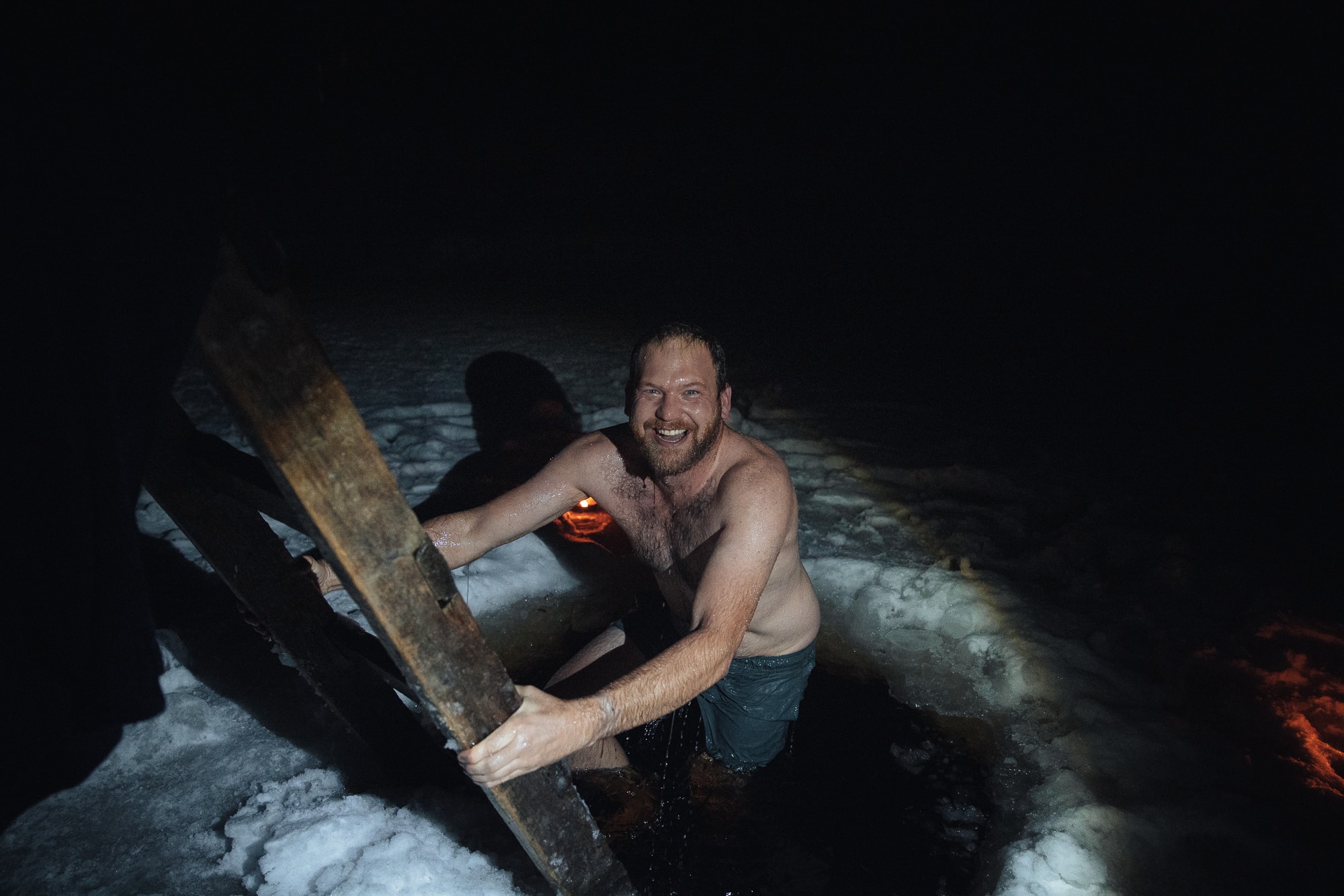 Mann mit Badehose im Eisloch in Finnland in der Dunkelheit