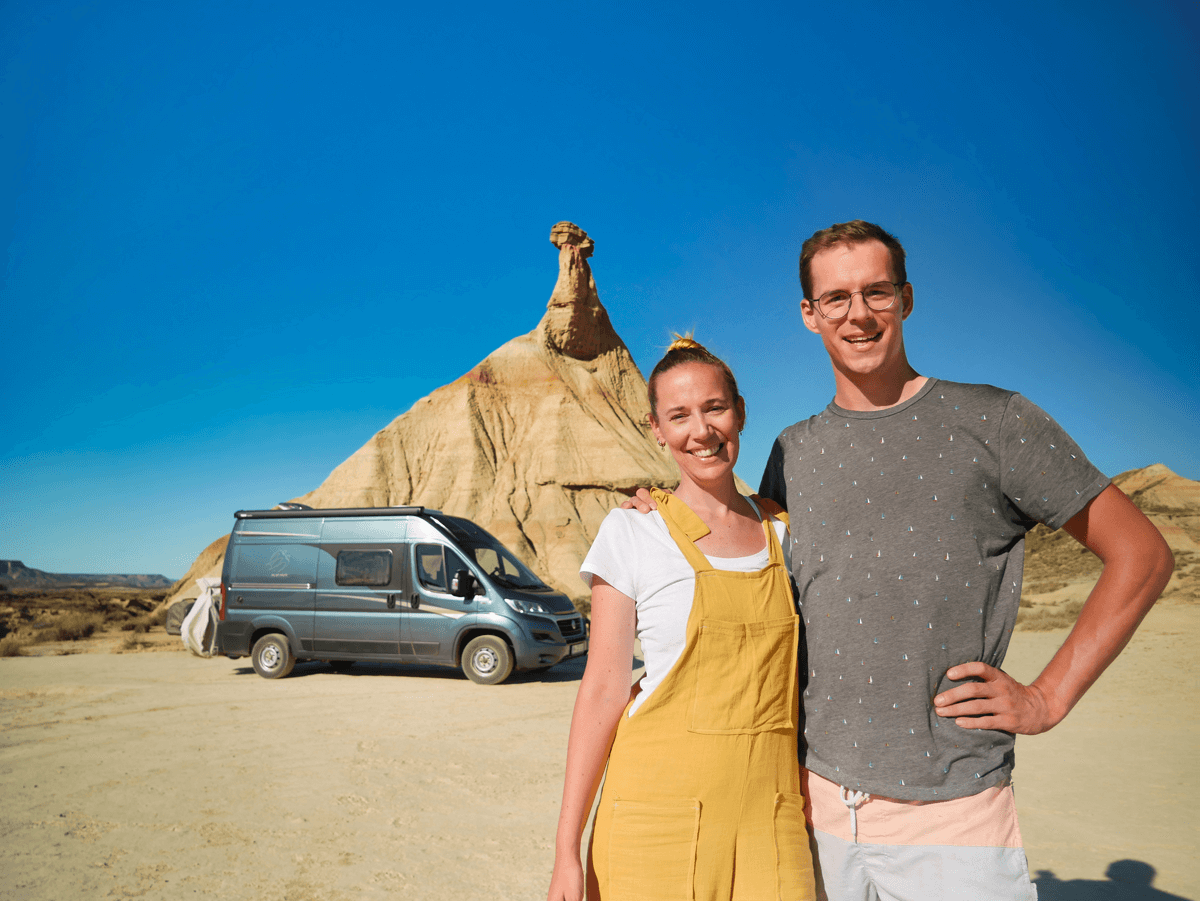 Mann und Frau vor Campervan in der Wüste