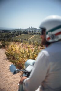 Mann genießt Aussicht auf San Gimignano bei seinem Vespa Trip durch die Toskana
