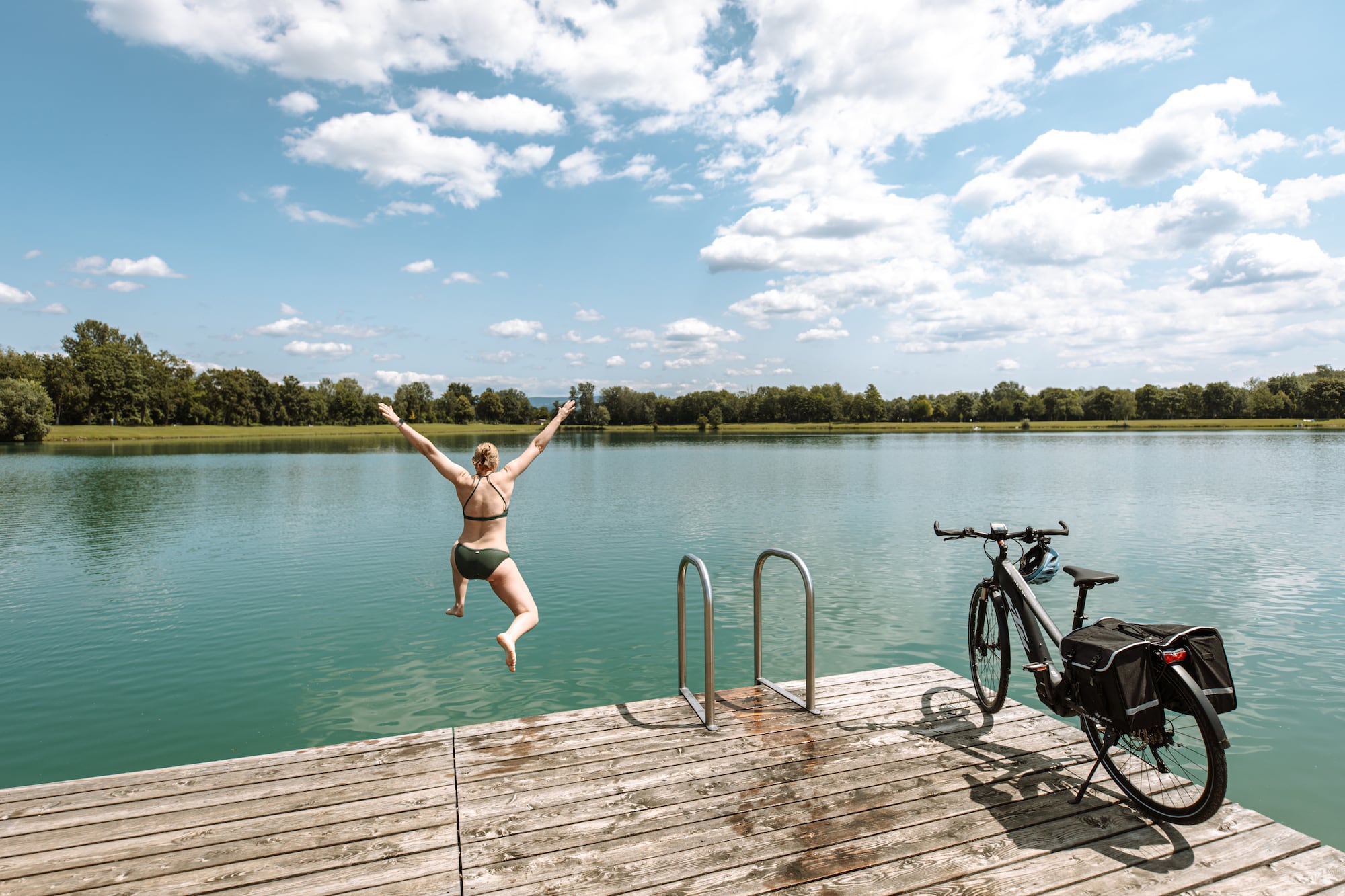 Frau springt auf Bikepacking-Tour zur Abkühlung in den See