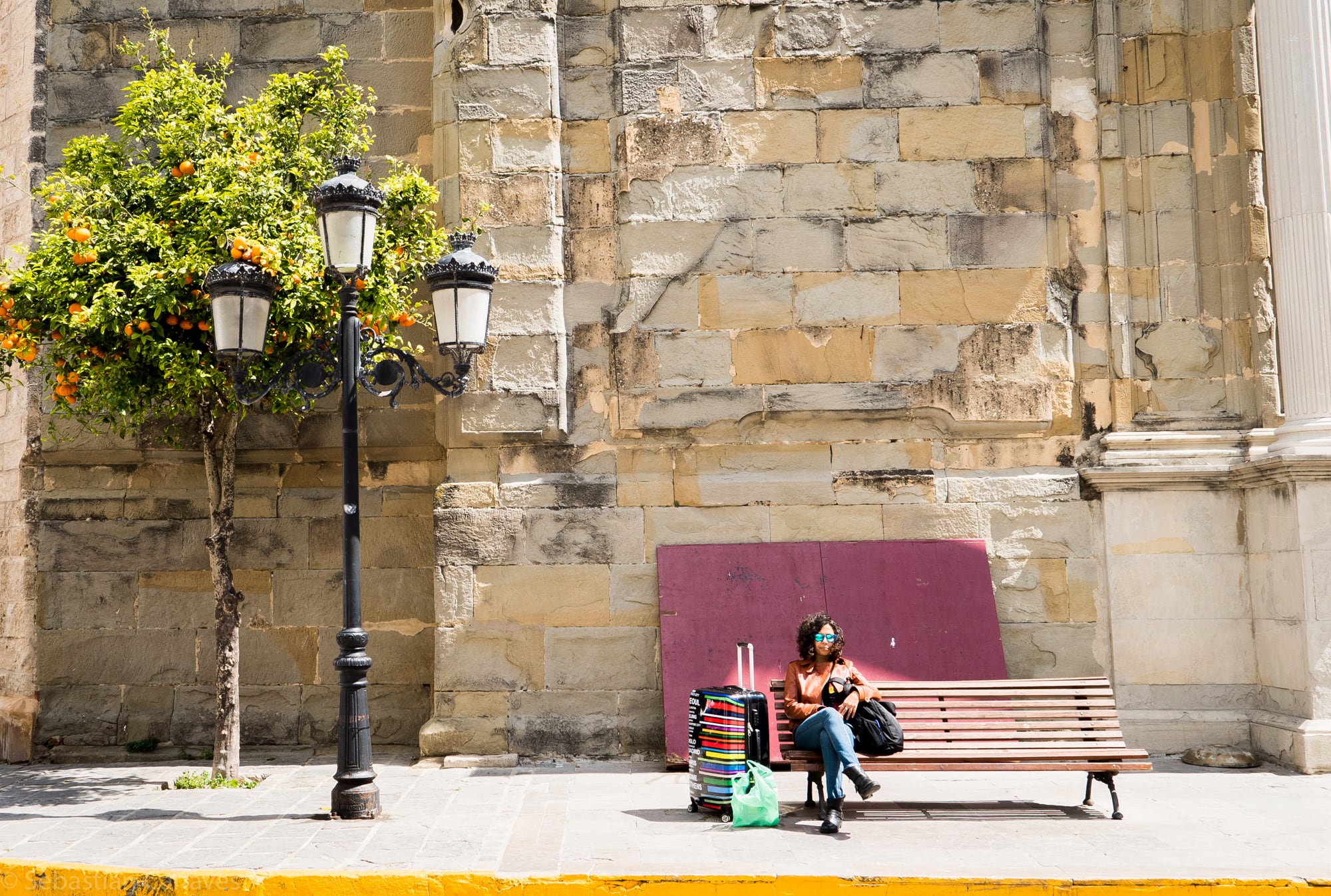 Handgepäck Maße: Frau sitzt auf einer Parkbank mit Handgepäck auf ihrer Reise