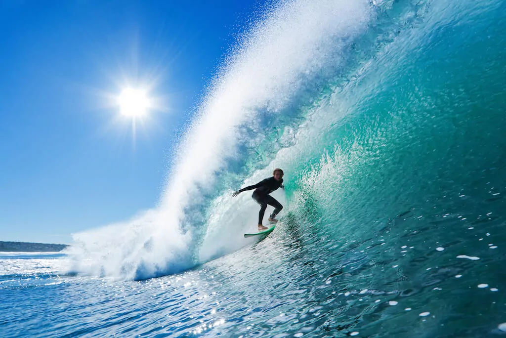 Ein Surfer surft auf einer Welle auf Hawaii - das perfekte Reiseziel im Winter mit Sonne.
