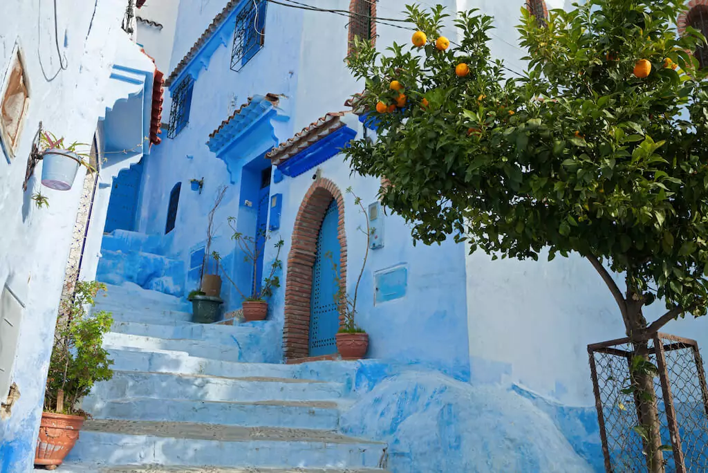 Blick in eine Gasse mit weiß-blauen Häusern in Marokko