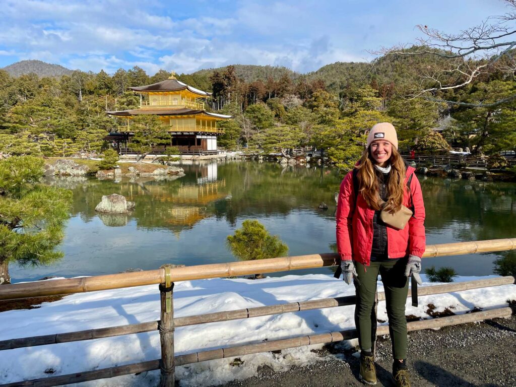 Frau steht vor einem See und einer japanischen Pagode