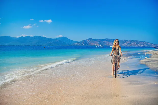 Work And Travel in Indonesien: Frau fähr Fahrrad am Strand der Gili Inseln