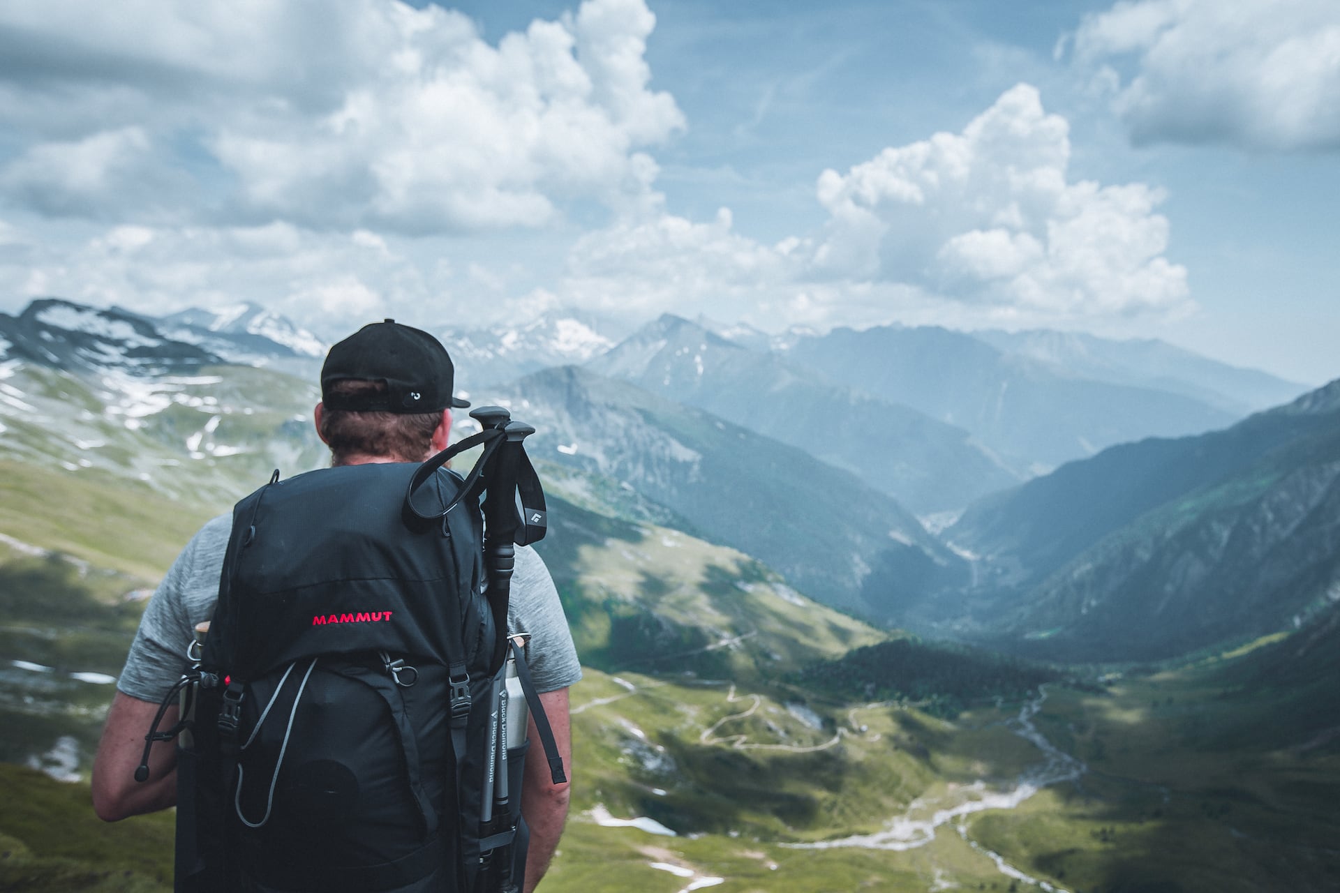 Fernwanderweg Österreich: Mann mit großem Rucksack blickt auf Bergkulisse