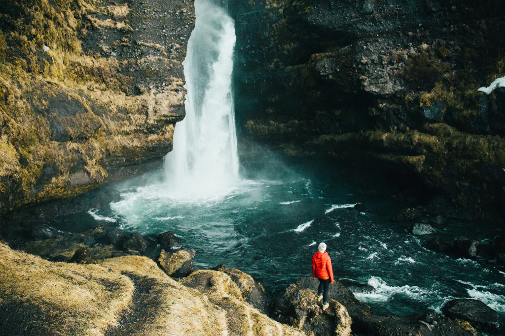 Reise Nach Island: Frau steht am Wasserfall