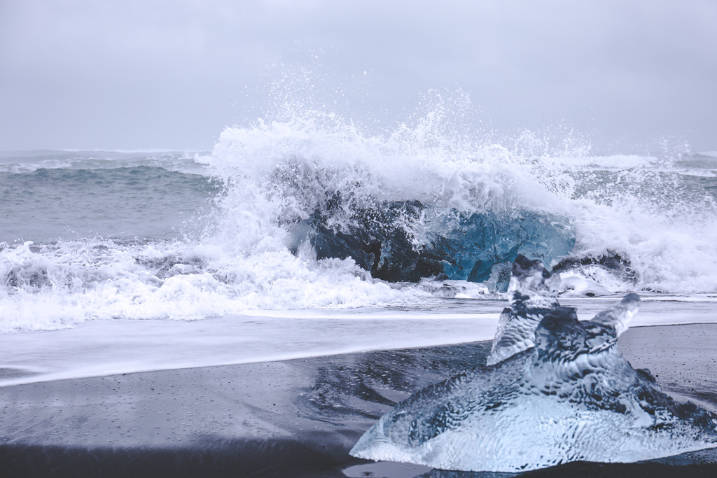 Hier siehst du die Wellen des Island Diamond Beach an einem Eisblock brechen.