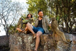 Mann und Frau sitzen auf einem Stein mit vier Affen in den Armen