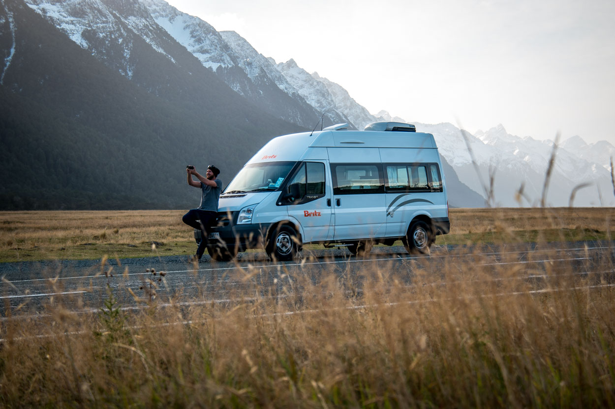 Tipps Reiseziele: Mann filmt sich vor seinem Camper mitten in einer Berg-Landschaft
