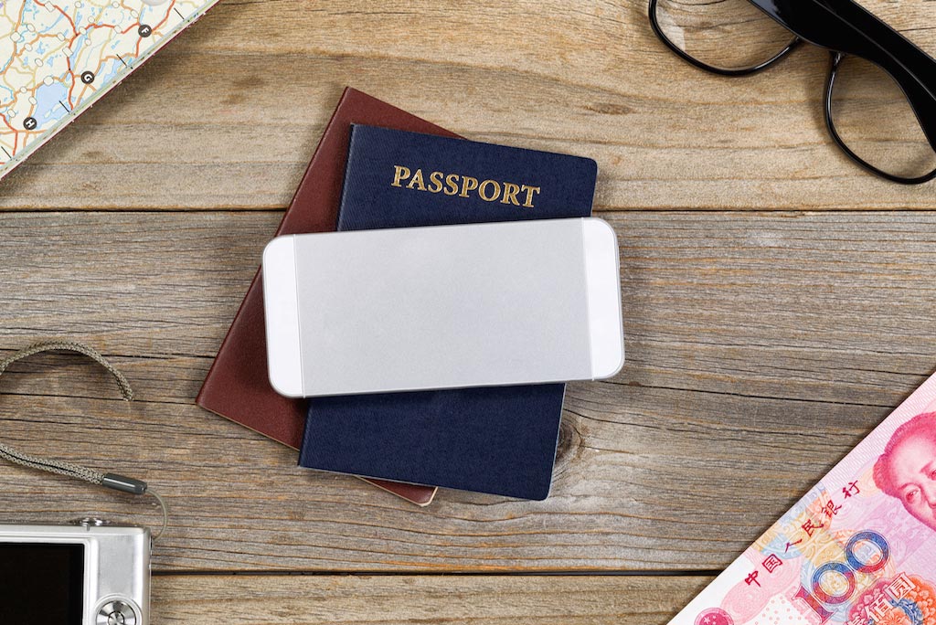 Urlaub App fürs Smartphone: Handy liegt mit Reisedokumenten für den Urlaub bereit