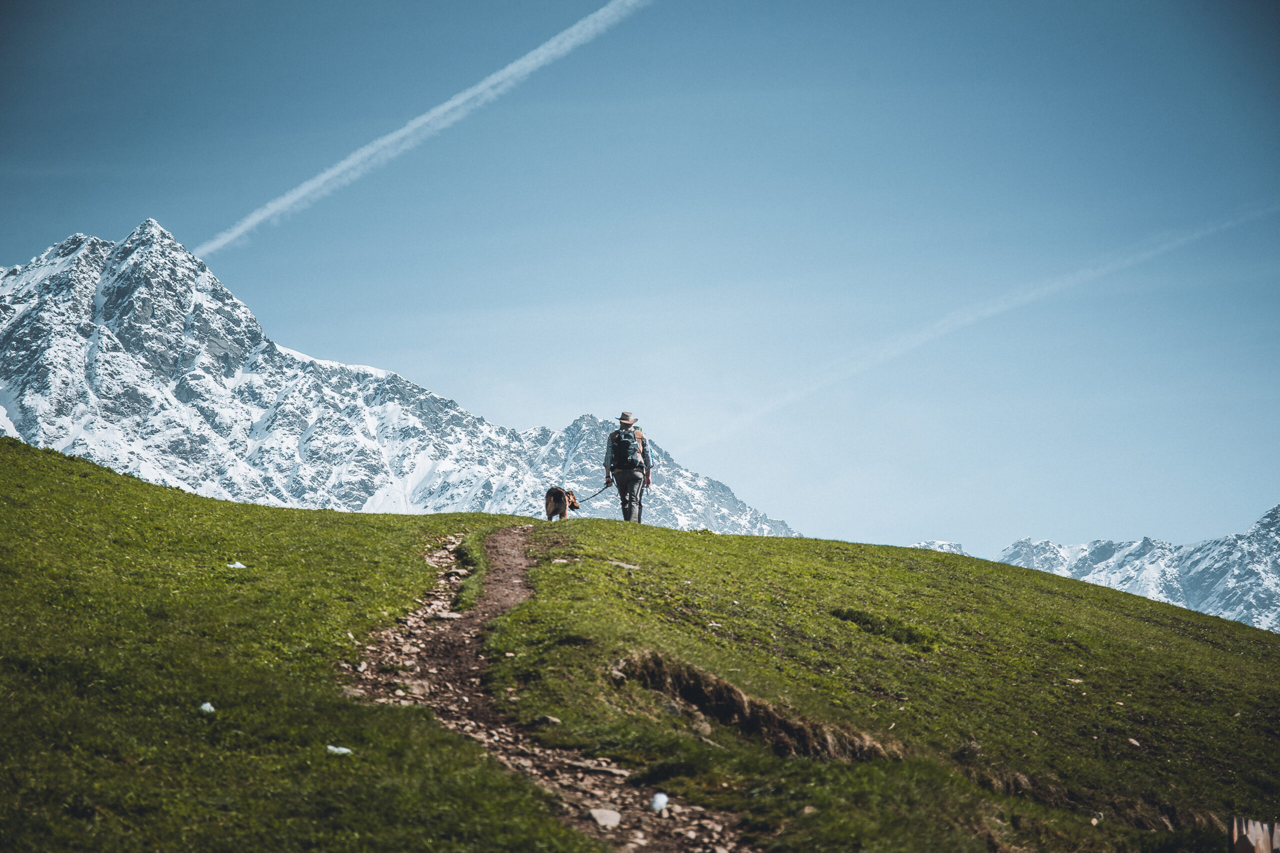 Eine Frau wandert in die Richtung einer schneebedeckten Bergspitze.