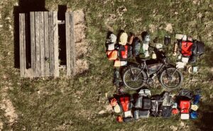 Ein Fahrrad liegt im Gras umgeben von vielen Taschen und Equipment